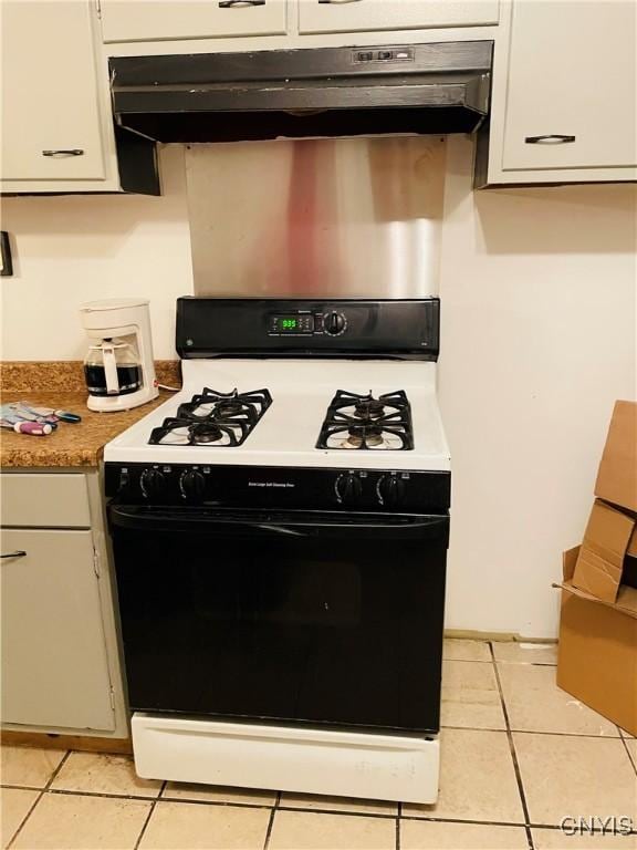 kitchen featuring white gas range oven, white cabinetry, and light tile patterned flooring