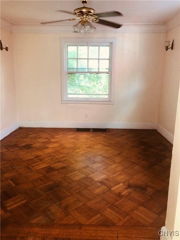 unfurnished room with dark parquet floors, ceiling fan, and crown molding