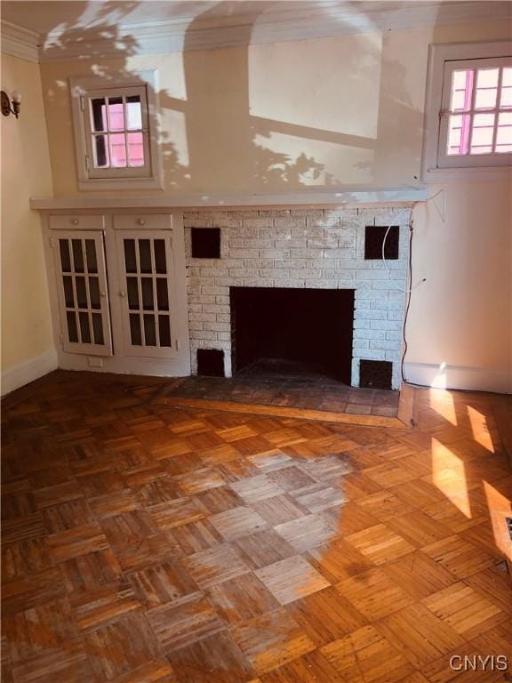 unfurnished living room with parquet flooring, crown molding, and a brick fireplace