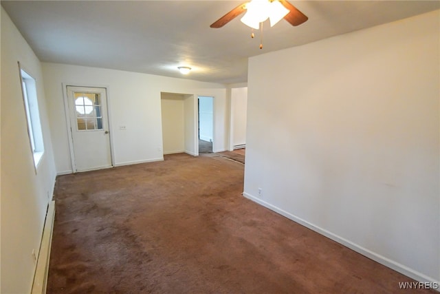 carpeted spare room with ceiling fan and a baseboard heating unit