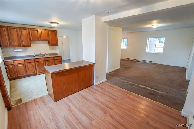 kitchen with kitchen peninsula, light wood-type flooring, a baseboard heating unit, and sink