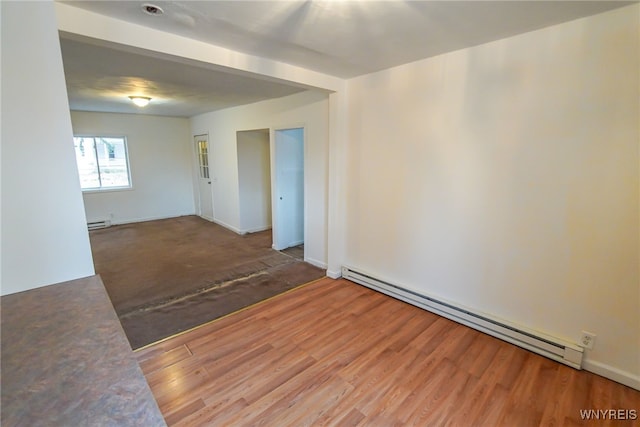 spare room featuring a baseboard radiator and wood-type flooring