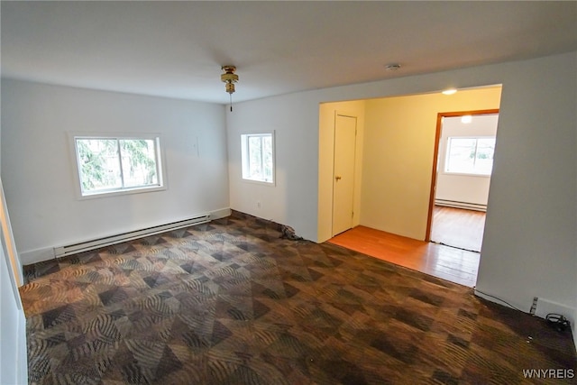 unfurnished room featuring baseboard heating and wood-type flooring