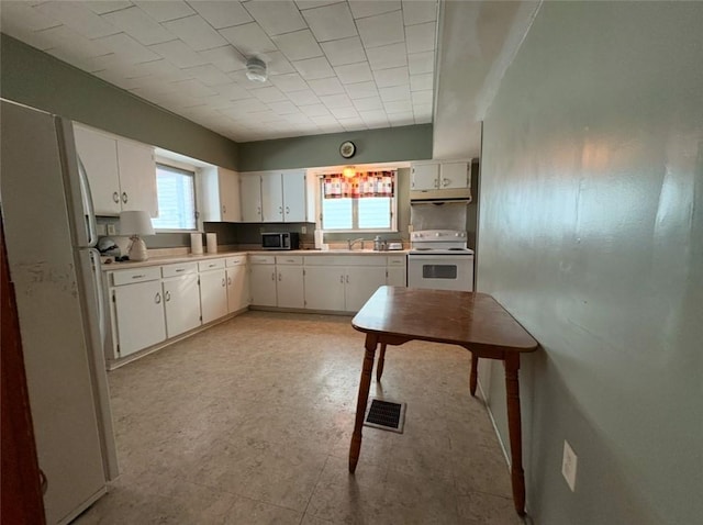 kitchen featuring sink, white cabinets, a healthy amount of sunlight, and white appliances