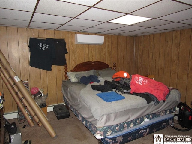 bedroom featuring a wall mounted air conditioner, a paneled ceiling, wood walls, and carpet floors