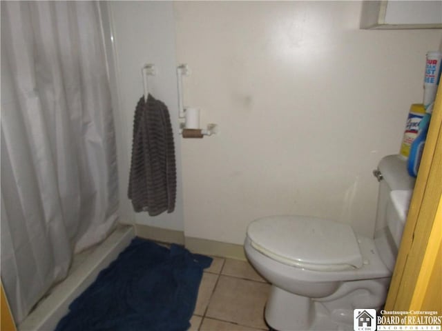 bathroom featuring tile patterned floors, curtained shower, and toilet