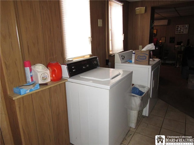 washroom with washing machine and clothes dryer, wood walls, and light tile patterned flooring