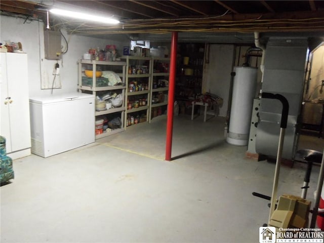 basement with electric panel, heating unit, refrigerator, and gas water heater