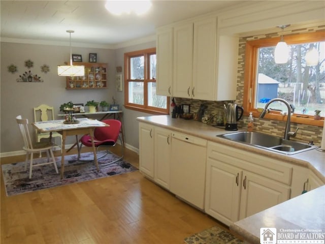 kitchen featuring pendant lighting, white dishwasher, sink, tasteful backsplash, and a healthy amount of sunlight