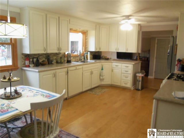 kitchen with white dishwasher, ceiling fan, sink, light hardwood / wood-style floors, and hanging light fixtures