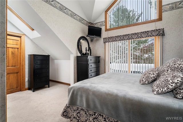 carpeted bedroom with lofted ceiling with skylight and access to outside