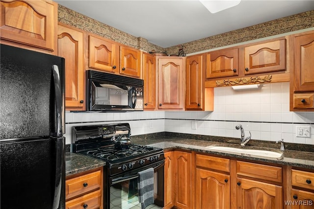 kitchen featuring sink, tasteful backsplash, dark stone countertops, and black appliances