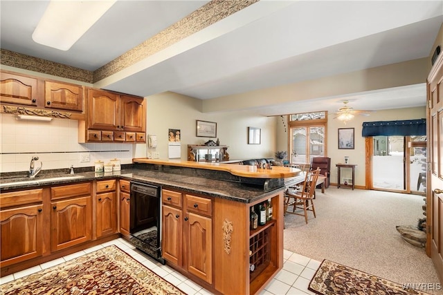 kitchen featuring light carpet, kitchen peninsula, ceiling fan, sink, and black dishwasher