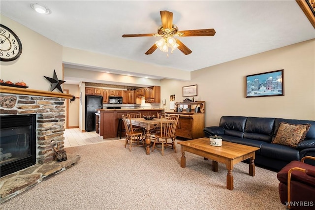 carpeted living room featuring ceiling fan and a fireplace