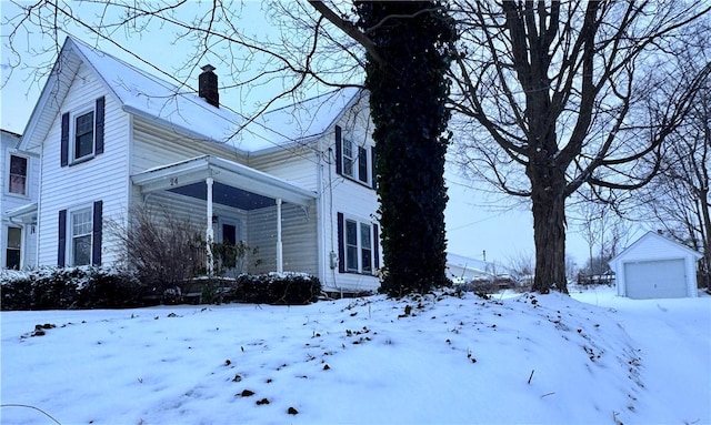 snow covered property with an outdoor structure and a garage