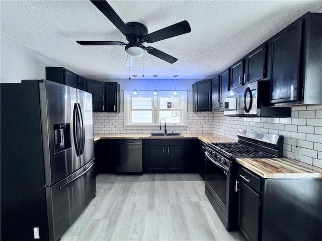 kitchen with wooden counters, stainless steel appliances, tasteful backsplash, and sink