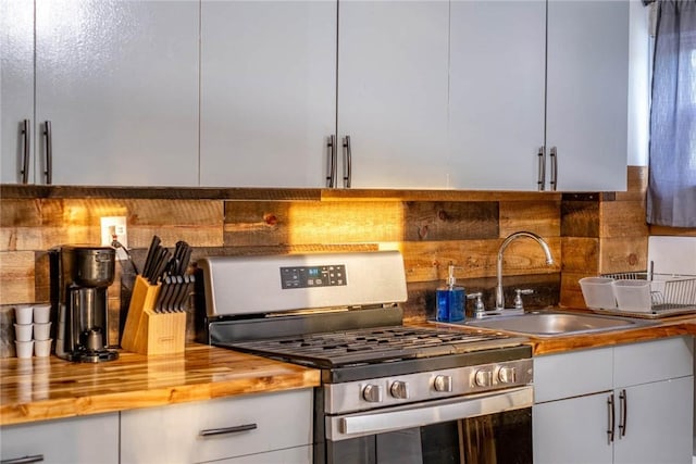 kitchen with butcher block countertops, decorative backsplash, sink, and stainless steel gas range