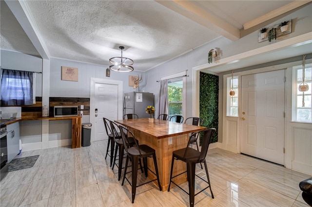 dining area with a notable chandelier, beam ceiling, ornamental molding, and a textured ceiling