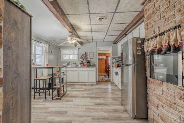 kitchen with stainless steel refrigerator, ceiling fan, light hardwood / wood-style floors, a paneled ceiling, and white cabinets