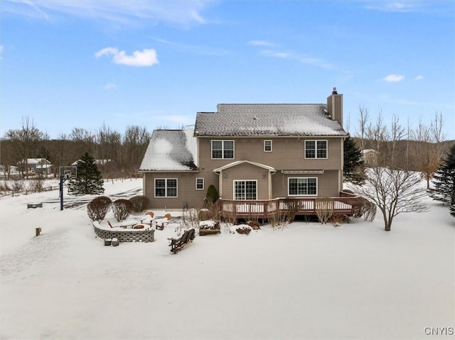 snow covered house featuring a deck and an outdoor fire pit