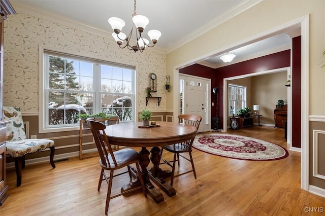 dining space with a notable chandelier, light wood-type flooring, and crown molding