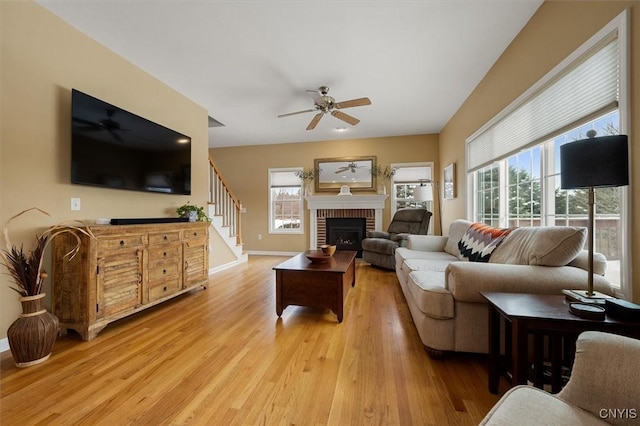 living room with ceiling fan, a fireplace, and light wood-type flooring