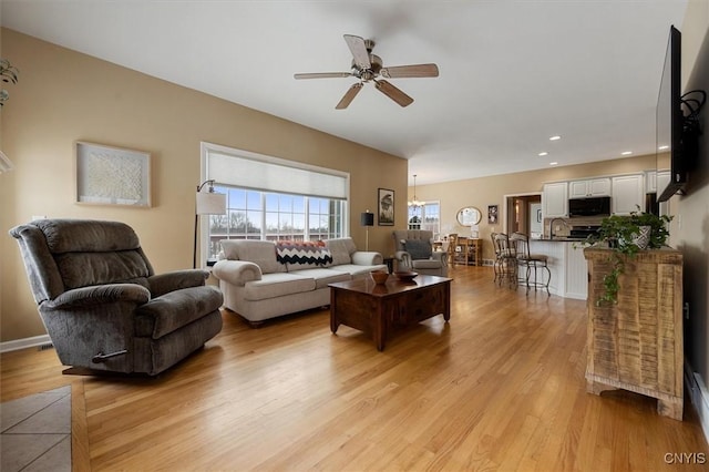 living room featuring ceiling fan and light hardwood / wood-style flooring