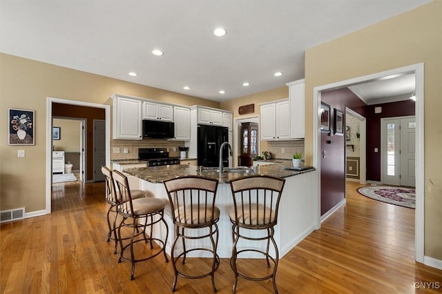 kitchen featuring black appliances, white cabinetry, and backsplash