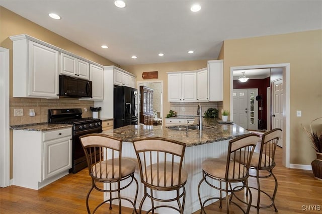 kitchen featuring black appliances, white cabinets, kitchen peninsula, and sink