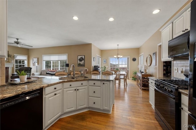 kitchen with kitchen peninsula, white cabinetry, sink, and black appliances