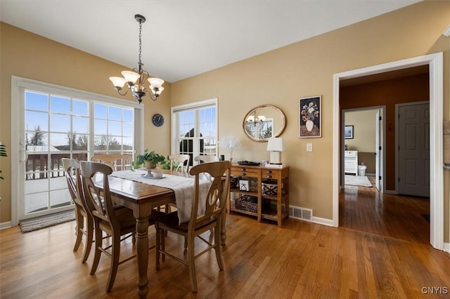 dining space with hardwood / wood-style flooring and a chandelier