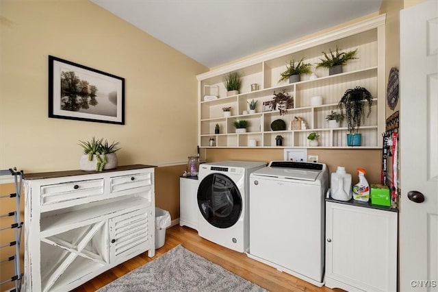 washroom with washer and dryer, light hardwood / wood-style floors, and cabinets