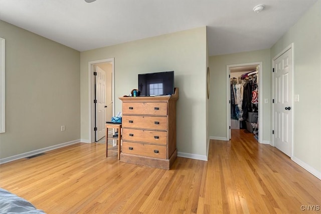 bedroom with light wood-type flooring, a walk in closet, and a closet