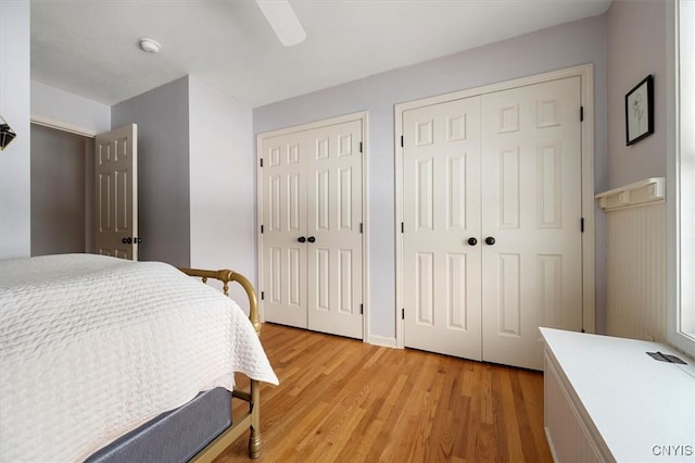 bedroom with multiple closets, ceiling fan, and light hardwood / wood-style flooring