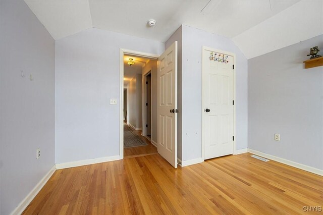 unfurnished room featuring light hardwood / wood-style flooring and vaulted ceiling