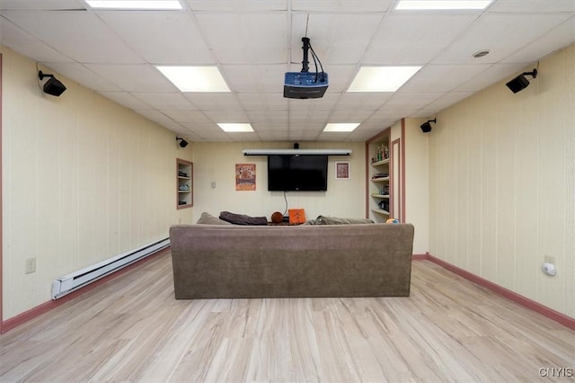 living room with built in shelves, a paneled ceiling, light hardwood / wood-style flooring, and baseboard heating