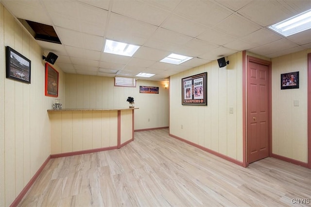 interior space with a paneled ceiling and light hardwood / wood-style floors