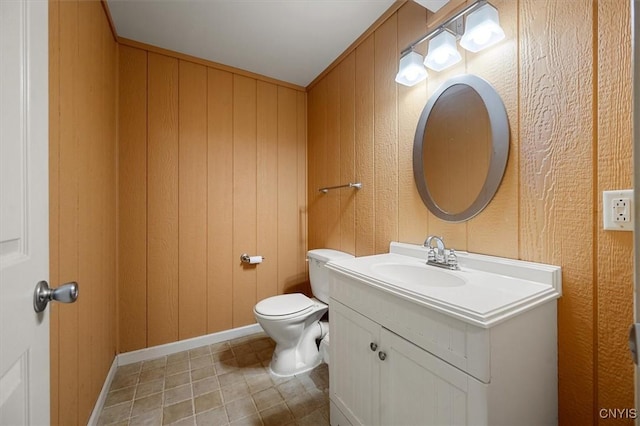 bathroom with vanity, wood walls, and toilet