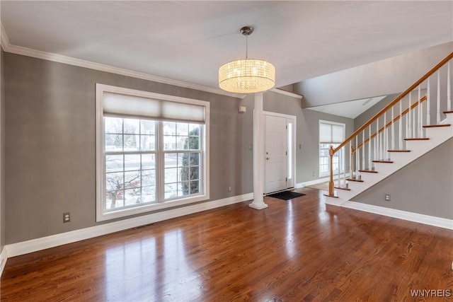 foyer entrance with hardwood / wood-style flooring, crown molding, and an inviting chandelier