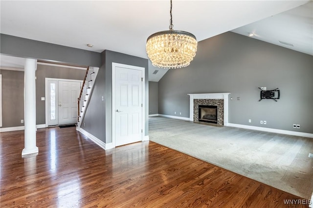 unfurnished living room featuring a fireplace, dark hardwood / wood-style flooring, lofted ceiling, and a notable chandelier