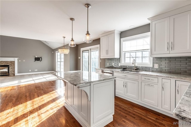 kitchen featuring decorative backsplash, decorative light fixtures, a breakfast bar area, white cabinets, and lofted ceiling