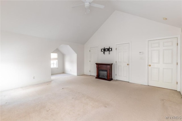 unfurnished living room with ceiling fan, high vaulted ceiling, and light colored carpet