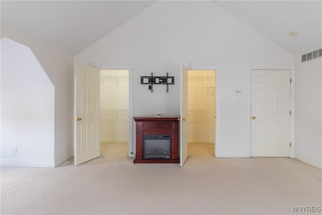 unfurnished living room featuring light carpet and high vaulted ceiling