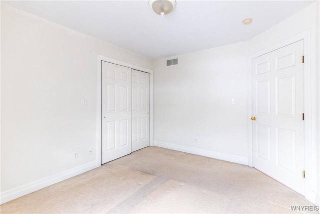 unfurnished bedroom featuring a closet and light colored carpet