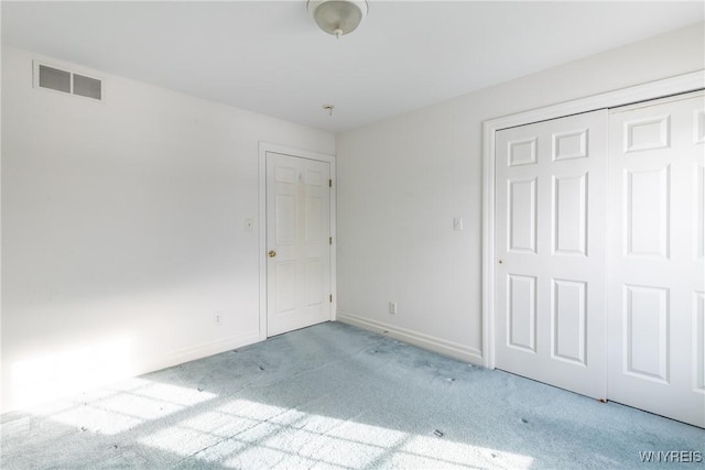 unfurnished bedroom with light colored carpet and a closet