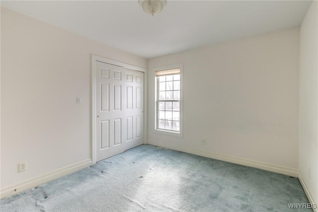 unfurnished bedroom featuring light carpet and a closet