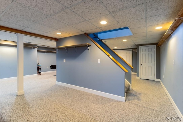 basement featuring a paneled ceiling and carpet