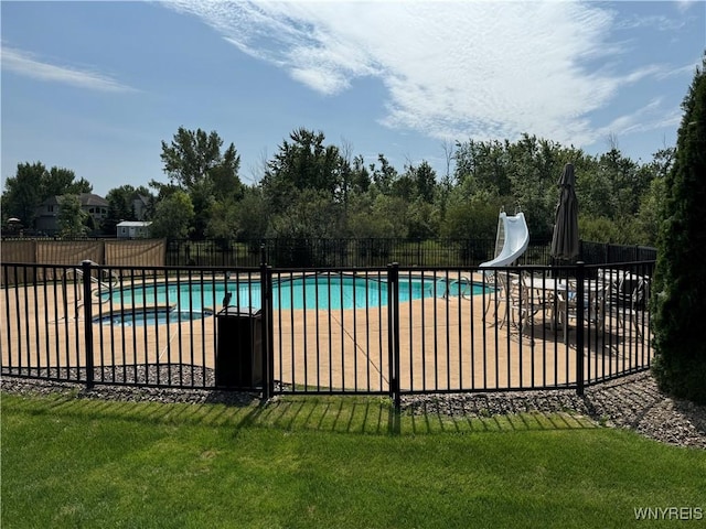 view of swimming pool with a patio area, a yard, and a water slide