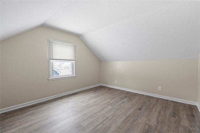 additional living space with wood-type flooring and vaulted ceiling