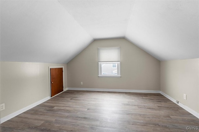 bonus room with dark wood-type flooring and vaulted ceiling